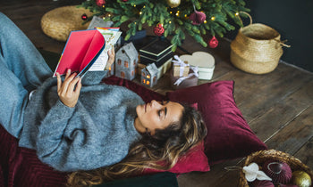 Frau liest unter Weihnachtsbaum