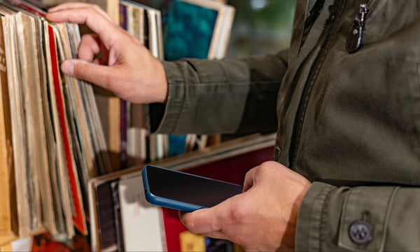 Person mit Smartphone vor Plattenregal